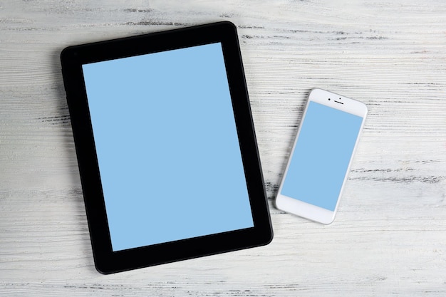 Moderne mobiele telefoon en tablet op witte houten achtergrond