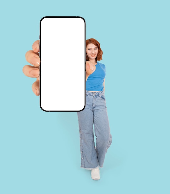 Moderne mobiele telefoon mock up volledige lichaamslengte weergave roodharige jonge blanke aantrekkelijke vrouw permanent