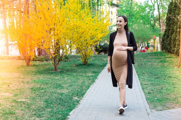 Moderne mooie zwangere wandelen op stadspark zwanger buitenshuis