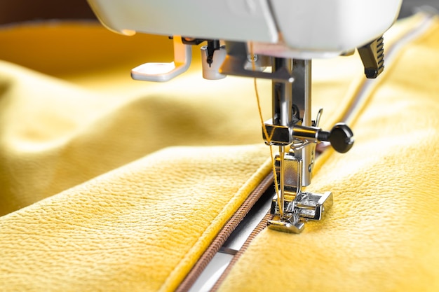 Moderne naaimachine en gele stof Naaiproces handgemaakte hobby DIY zakelijke reparatie