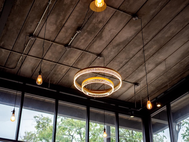 Moderne plafondlamp en gloeilampen die aan een houten plafond hangen in een gebouw in loftstijl