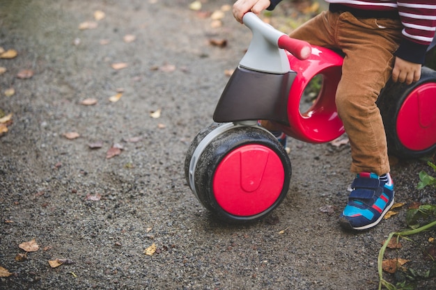 Moderne plastic kinderfiets met kleine jongen in het park