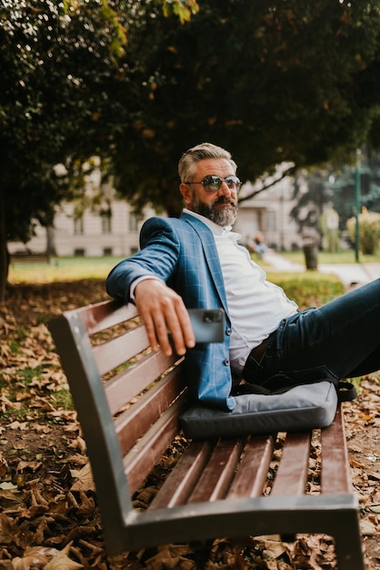 Moderne senior zakenman rustend op een bankje in de stad tijdens een pauze van het werk