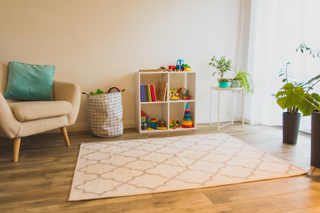 Moderne speelkamer voor kinderen op kinderdagverblijf of kleuterschool Witte plank gezellige fauteuil bloemen en licht tapijt alles voor kinderen veiligheid en comfort