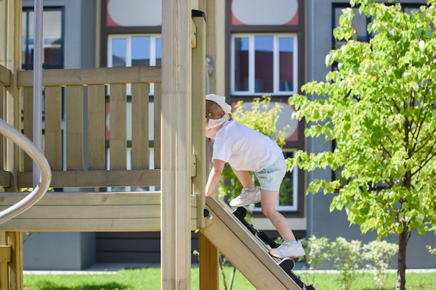 Moderne speeltuin Het meisje beklimt een houten glijbaan Outdooractiviteiten Zomerentertainment