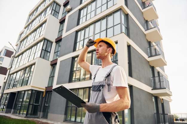 Moderne stad Jonge man aan het werk in uniform bij de bouw overdag