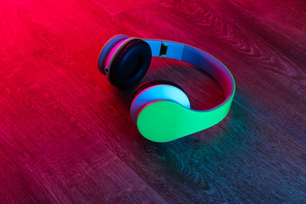 Moderne stereo draadloze koptelefoon op houten oppervlak met neon rood blauw licht