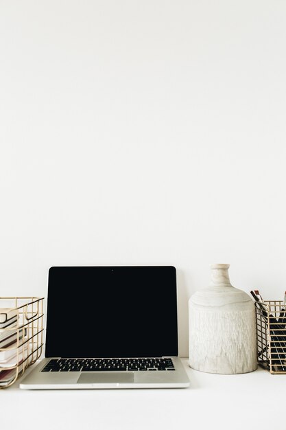 Moderne stijlvolle kantoor aan huis bureau werkruimte met lege mockup scherm laptop, briefpapier op wit