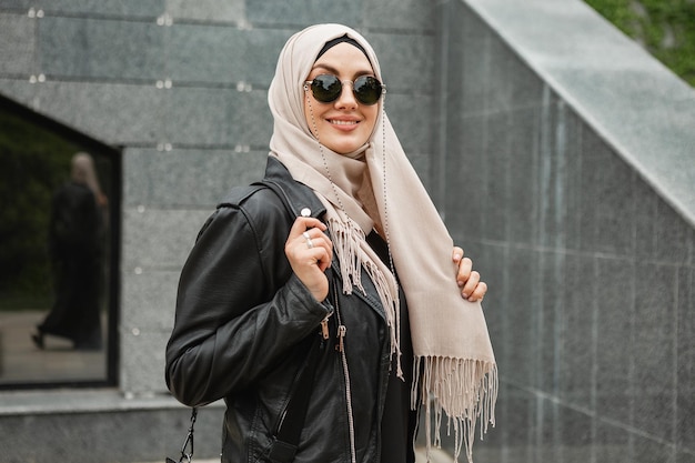 Moderne stijlvolle moslimvrouw in hijab in stadsstraat