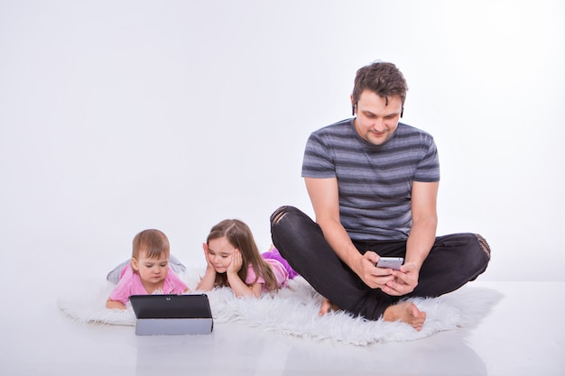 Moderne technologieën in het dagelijks leven: een man praat aan de telefoon via een headset, kinderen kijken naar een cartoon op een tablet.