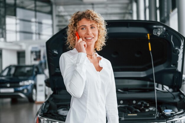 Foto moderne technologieën vrouw met krullend blond haar is in autosalon