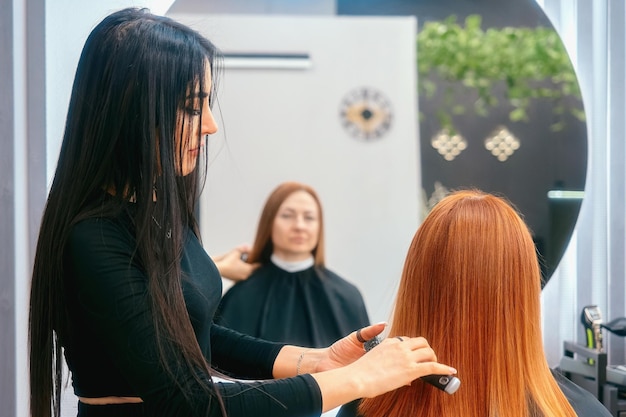 Moderne trendy schoonheidssalon Vrouw stylist doet haar en haarstyling aan de klant