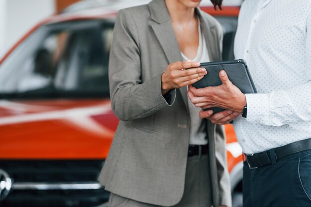 Moderne voertuigen Man in formele kleding die klant helpt bij de keuze van de auto