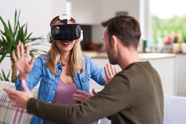 Moderne vrouw die virtual reality-simulator in de woonkamer gebruikt