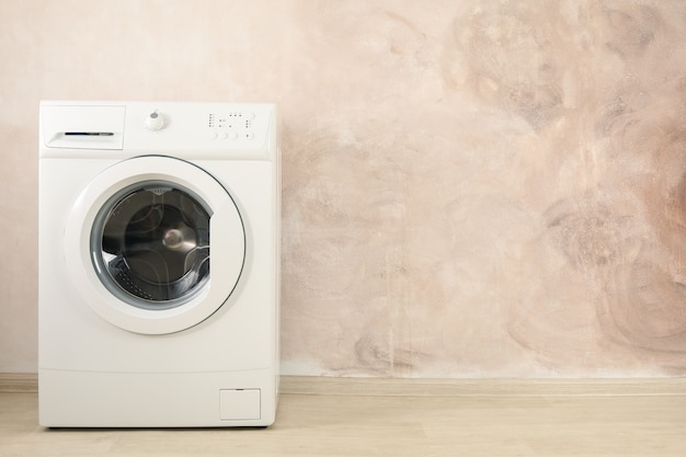 Moderne wasmachine tegen bruine muur, ruimte voor tekst