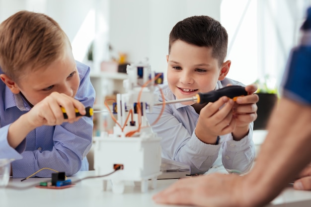 Moderne wetenschap. Positieve blije jongens die een robot bouwen terwijl ze een wetenschapsklas hebben