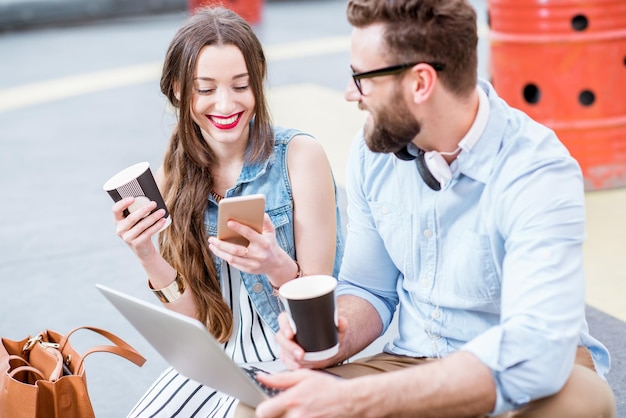 Moderne zakenman en zakenvrouw werken met laptop en koffie buitenshuis op de grond van de helihaven. Lifestyle bedrijfsconcept