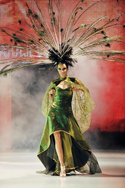 modeshow catwalk met mooie jonge vrouw in elegante en luxe jurk met vogel pauwenveer decoratie