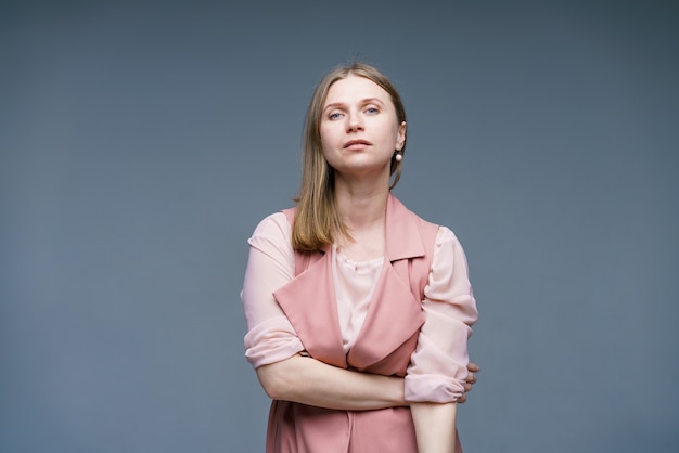 Modest and naive woman with blond hair stylishly dressed in pink vest and shirt happy studio shot of...