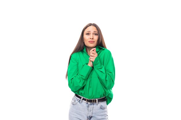 Modest wellgroomed brunette longhaired young woman in a green shirt on a white background with copy