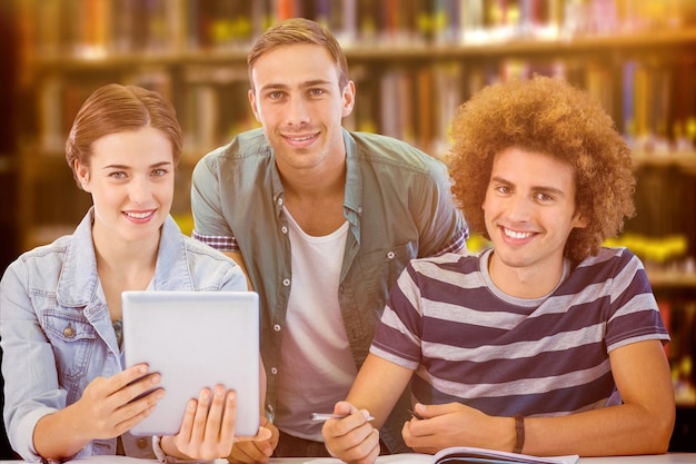 Modestudenten die tablet gebruiken tegen close-up van een boekenplank