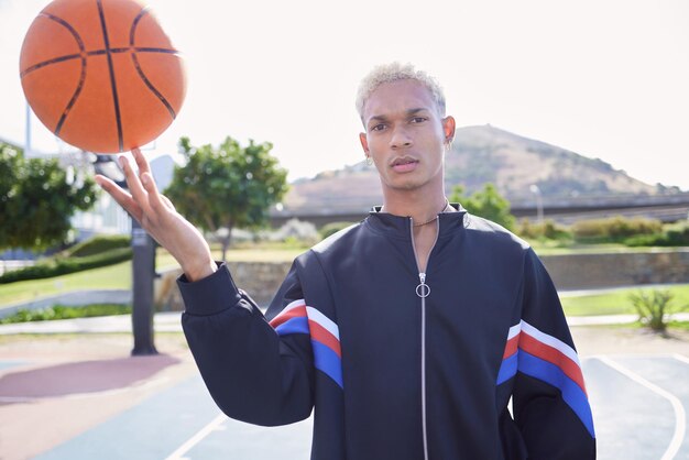 Modeveld en man die een basketbal draait op het sportveld voor een trainingsoefening of cardiotraining buitenshuis Portretbalans en jonge speler in een cool stedelijk jasje met bal aan vinger