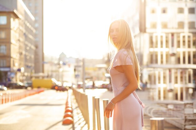 Modieus blond model poseren op straat in een stralen van de zon. Straatstijlconcept. Ruimte voor tekst
