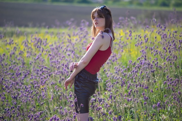 Modieus portret van een jong mooi meisje in een veld met bloemen