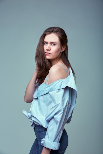 Modieus portret van mooie jonge vrouw met blauwe ogen over grijze achtergrond