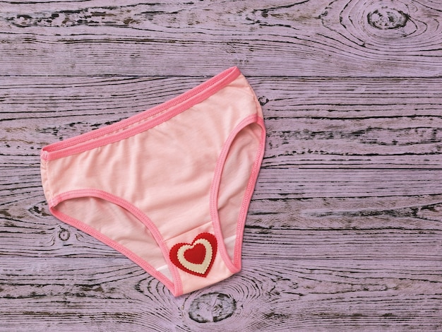 Modieus roze damesslipje met rood hart op roze houten lijst. Vrouwen ondergoed. Plat leggen.