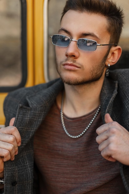 Modieus stedelijk portret van stijlvolle zakenman hipster man met zonnebril in trendy jas op straat