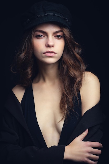 Modieus studioportret van een mooi jong model in zwarte hoed en sexy top Low key