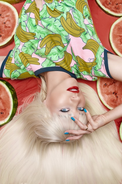 Modieuze blonde met make-up die dichtbij watermeloenen ligt