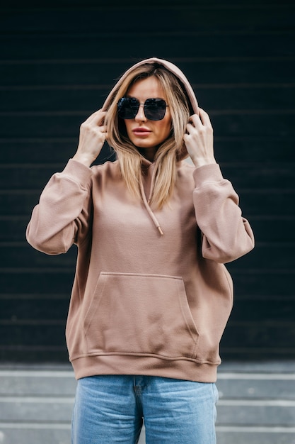 Modieuze blonde vrouw in bruine oversized hoodie