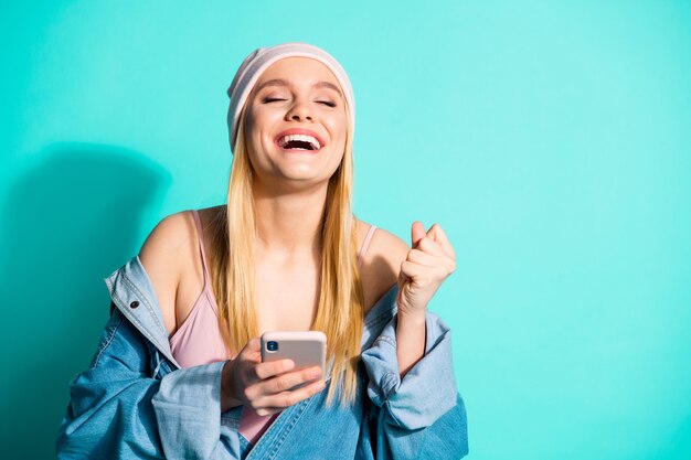 Modieuze blonde vrouw poseren tegen de blauwe muur