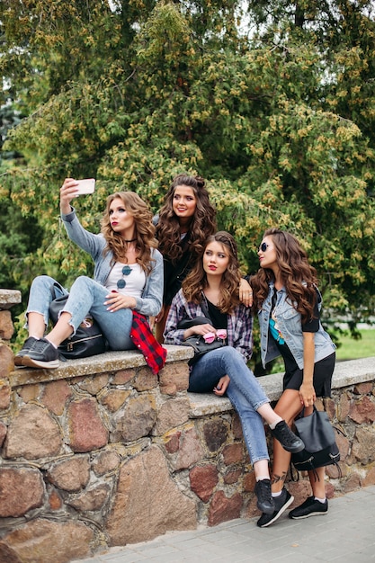 Modieuze dames met kapsel nemen selfie buitenshuis.