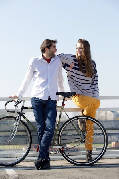 Foto modieuze jonge man en vrouw poseren met fiets buitenshuis