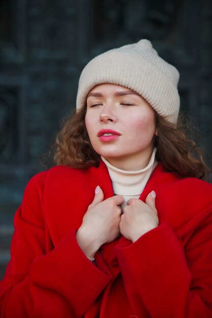 Modieuze jonge mooie stijlvolle vrouw in rode jas lopen op straat. Herfstmodetrend voor lachende, vrolijke, doelgerichte vrouwen. Conceptstijl, mode, schoonheid en prestatiedoelen. Ruimte kopiëren