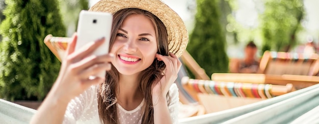 Modieuze jonge mooie vrouw die lacht en selfie neemt op mobiele telefoon die videoconferentiegesprek voert