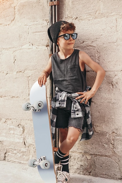 Foto modieuze jongen met skateboard in de stad