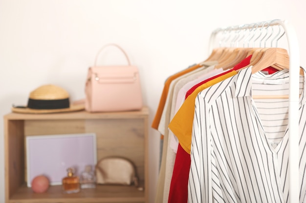 Modieuze kleding op hangers op een garderoberek op de achtergrond van de kamer