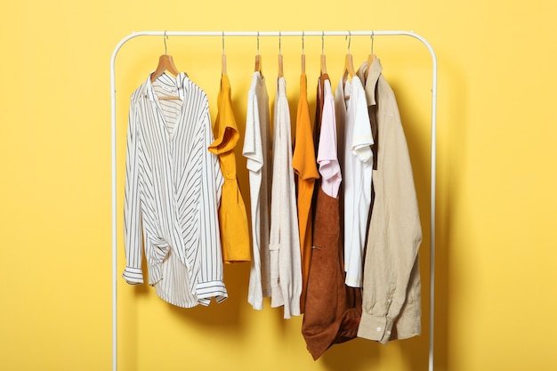 Modieuze kleding op hangers op een garderoberek op een gekleurde achtergrond