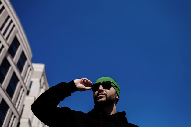 Modieuze knappe man draagt een zonnebril tegen de blauwe lucht. kopieer ruimte