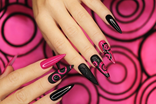 Modieuze roze en zwarte manicure op lange scherpe nagels