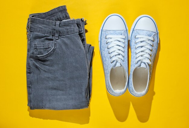 Modieuze sneakers en jeans geïsoleerd op geel