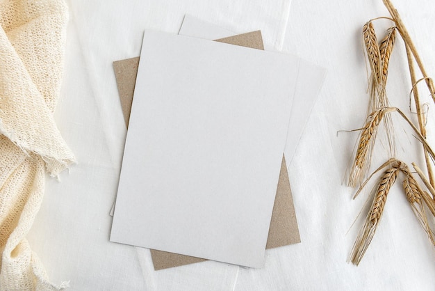 Modieuze voorraad briefpapier achtergrond een witte kaart en takjes tarwe oren op een witte tafel Romantische achtergrond Blanco voor een uitnodigingskaart