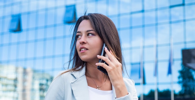 Modieuze vrouw draagt een formeel pak in de straat buiten en spreekt aan de telefoon zakenvrouw