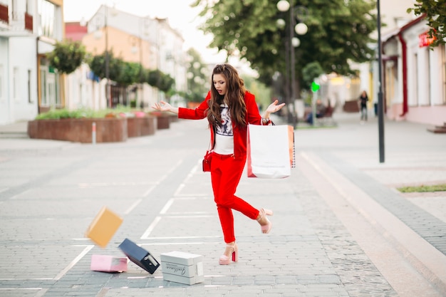 Modieuze vrouw in rood pak met boodschappentassen liet schoenendozen in de straat vallen.