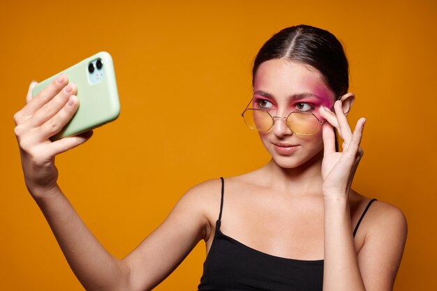 Modieuze vrouw lichte make-up poseren zwarte trui met een telefoon in de hand geïsoleerde achtergrond ongewijzigd