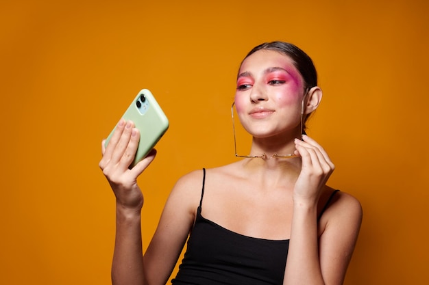 Modieuze vrouw lichte make-up poseren zwarte trui met een telefoon in de hand geïsoleerde achtergrond ongewijzigd